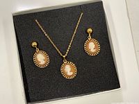 Full view of gold tone chain necklace with cameo pendant and matching earrings displayed in black gift box.