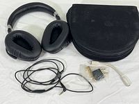 Sennheiser headphones, black zippered case and various accessory cables and adapters on white background