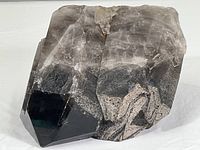 Large smoky black natural quartz specimen showing polished facets and rough quartz surfaces, flat polished base visible.