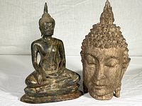 Both seated metal Buddha statue and ceramic Buddha head front view