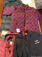 Four ladies jackets: green Eddie Bauer jacket, patterned pink geometric jacket, pink jacket, and navy blue Eddie Bauer coat with red lining and Angels Flight logo