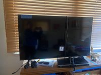 50 inch LG smart TV shown front view with power cables and remote on table below.