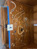 Overview of jewelry pieces on wooden surface, showing necklaces, bracelets, earrings and rings spread out