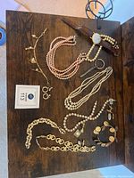 Overall view of watch, necklaces, bracelets, cufflinks and earrings on wooden surface