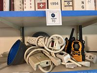 Shelf assortment showing two Motorola walkie-talkies, two handheld fans (one blue grille, one gray), multiple white power strips, and a small white adapter.