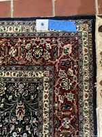 Close-up image showing burgundy border with floral pattern and fringes on the short side. Dimensions 75 x 54 (inches) noted on a tag.