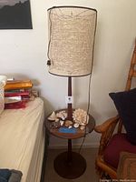 Full view of lamp with integrated side table and shells placed on table surface.