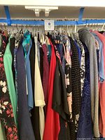 Full rack view showing assorted womens plus size clothing in various colors and patterns, hung on hangers.