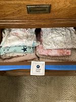 Drawer open showing folded women's nightgowns in pastel colors and floral prints, size XL indicated