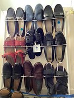 Top view of 10 pairs of women's shoes arranged on a metal rack, including sandals, loafers, and everyday shoes in various colors and materials.