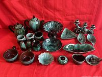 Full view of 21 piece Blue Mountain Pottery set arranged on red cloth background showing all items from a front angle.