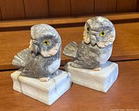 Front angle of both marble/soapstone owl bookends with detailed feather patterns and yellow eyes on book-shaped bases