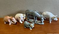 Front view of five marble animal figurines arranged side by side on wooden surface against plain background.