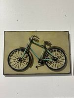 Front view of metal bicycle wall art mounted on a rectangular plaque showing detailed bike components including tires, handlebar, pedal and seat.