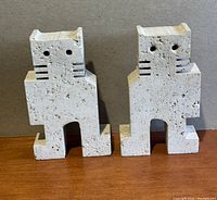 Front view of both travertine cat bookends showing geometric stylized cat shapes and pitted surface texture