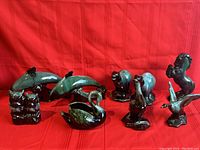 All nine Blue Mountain Pottery animal figurines on a red background showing various animal designs including dolphins, swan, bears, squirrel, horse, and seagull.