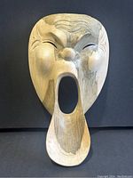 Front view of the wooden mask showing detailed carved facial features and large open mouth
