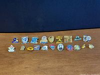 Single image showing 20 vintage sports pins arranged in a row with various designs, helmets, footballs, logos, and numbers.