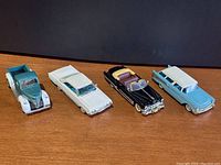 Four vintage toy cars in a row against a black background showing side and front views