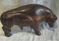 Side view of the wooden standing buffalo statue showing smooth contours and detailed carving of the horns and legs.