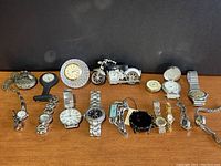 Front view of mixed watch set including wristwatches, pocket watches, a motorcycle clock, and a watch in a crystal-like display case.