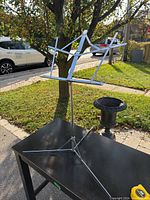 Music stand set outside on a table showing full structure, tripod base, and adjustable mechanism.