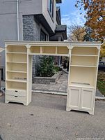 Full view of the three-piece white wall unit with shelving, drawers, and cabinet, showing central open space, scuffs visible.