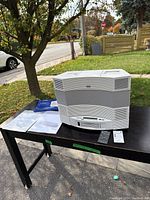 Overall view of Bose system, two remotes and manuals on table outdoors