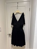 Black Diane von Furstenberg black wrap dress on a hanger showing V front and V back style