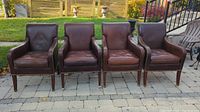 Four brown leather armchairs lined up outdoors showing quantity and overall style.
