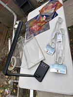 Lot items arranged on white outdoor table showing pillowcases, towel bars, UV black light, and Lucite display tower.