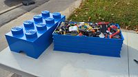 Full view of blue Lego storage box open with mixed Lego pieces inside.
