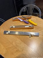 Three magnetic utensil holders displayed on table: one stainless steel long bar and two shorter wooden bars with magnetic strips.