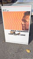 Front view of the Paul Newman Cool Hand Luke movie plaque standing upright on pavement.