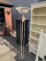 Full view of the tall freestanding floor lamp standing next to furniture pieces outdoors, showing the overall height and structure.