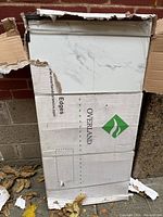 Two large rectangular ceramic tiles packaged in branded Overland cardboard boxes showing the white tiles with gray swirl marble-like finish.