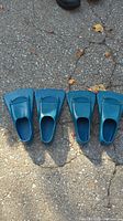 Overhead photo of two pairs of blue Zoomers scuba diver swim fins laid out on pavement, showing top view.