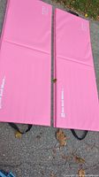 Two pink foldable exercise mats laid flat side-by-side, showing their size, segmented fold lines, and handles.