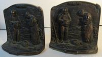 Front view of the pair of cast iron praying farmers scene bookends, showing detailed relief work with two figures on each piece.