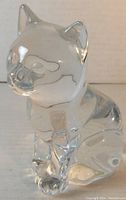 Front view of clear glass cat figurine showing facial features and front paws.
