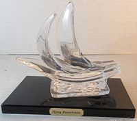 Clear glass stylized ship figure on black rectangular base with gold plaque reading 'Flying Douthman'