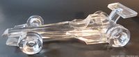 Photo showing right side profile of the clear glass F1 race car paperweight on dark surface.