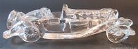 Side view of clear glass roadster paperweight showing detailed wheels and curved body.