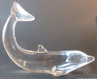 Clear crystal dolphin paperweight shown in profile, smooth transparent glass with curved tail upturned.