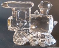 Crystal clear steam locomotive paperweight viewed from side showing detailed shaping of cab, chimney, and wheels with reflective crystal glass material.