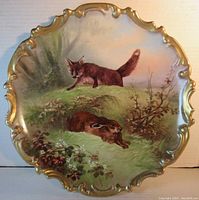 Front view of the scalloped porcelain plate showing the fox and rabbit in a natural setting with gold rim detail.