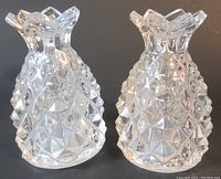 Front view of two clear crystal pineapple salt and pepper shakers, showing their faceted diamond-cut texture and the pineapple crown tops.