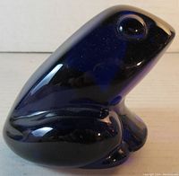 Close-up front angled view of cobalt blue crystal frog paperweight showing glossy surface and rounded contours.