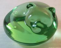 Green translucent crystal sleeping cat paperweight viewed from above and angled side showing smooth rounded details and sculpted ears.