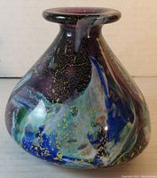 Photo showing front angle of the purple blown glass bottle with visible gold specks and streaks of blue, green, and white.